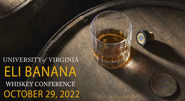Half-filled whiskey glass sitting atop a whiskey barrell