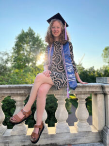 Mae Hovland seating on a column in graduation regalia