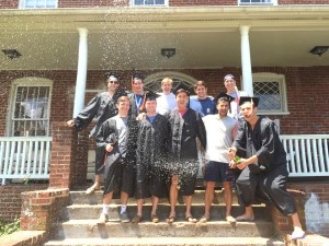 Image of graduating SAM brothers in their regalia on the front steps of the SAM house