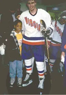 Old photo of UVA hockey player standing with a child.