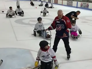Old photo of hockey player with lots of children on the ice.